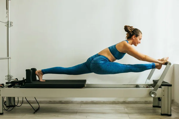 Mulher realizando exercícios de Pilates usando uma tabela Cadillac ou Trapeze